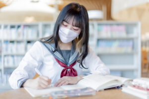 マスクをして勉強をする女子高生